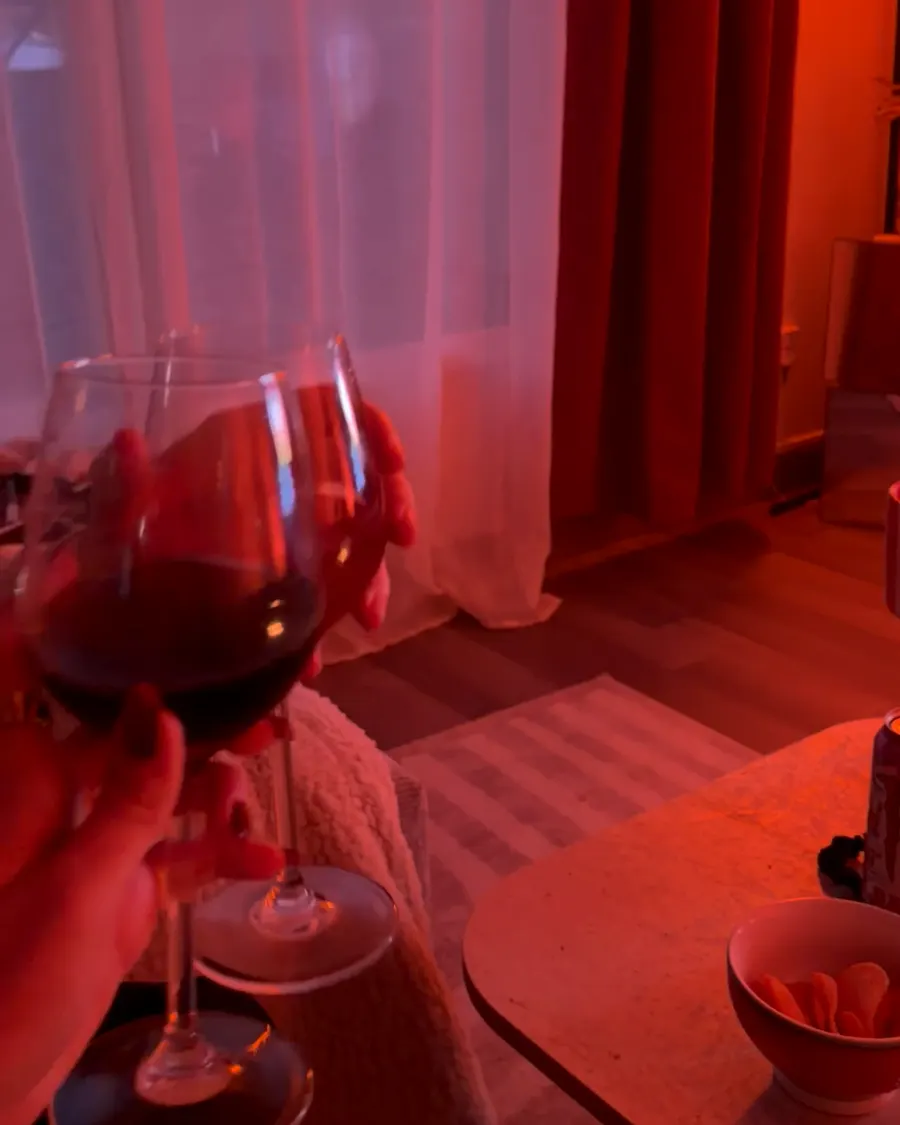 Two glasses of wine clink in front of the TV